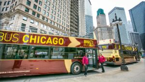two drivers standing beside the Big Bus Tour bus with skyline in the background in Chicago, Illinois, USA